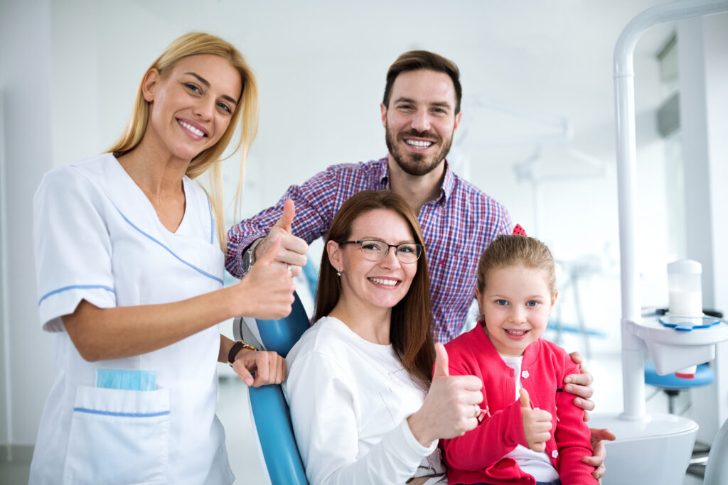 Happy family with their family dentist after a routine dental checkup in a modern dental office